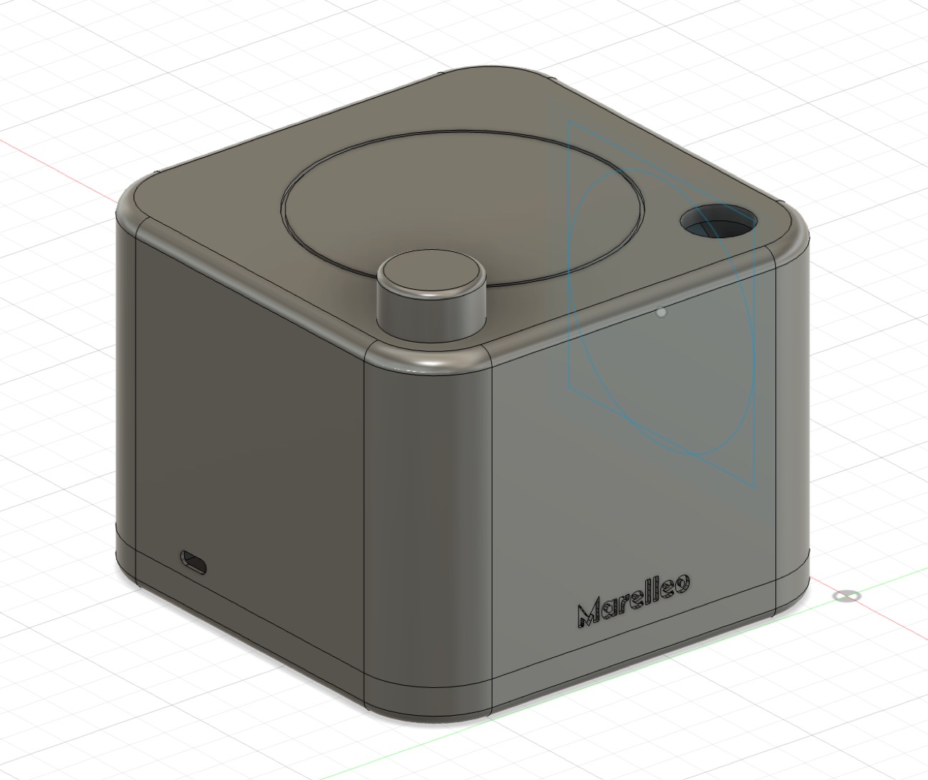 Le modèle 3D du boîtier dans Fusion 360 : un cube aux arêtes arrondies, avec un cercle sur le dessus, un bouton cylindrique et le nom gravé sur la face avant.