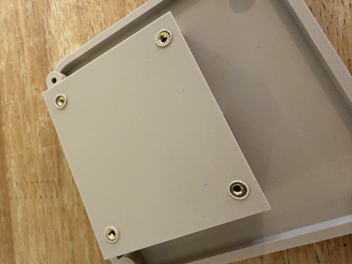 Le fond du boîtier imprimé avec des inserts en laiton noyés dans le plastique aux quatre coins.